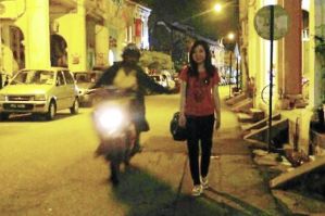 Caught in the act: The snatch thief attempting to grab Dai’s handbag at Love Lane in Penang. (Right) The suspect being kept under close watch.
